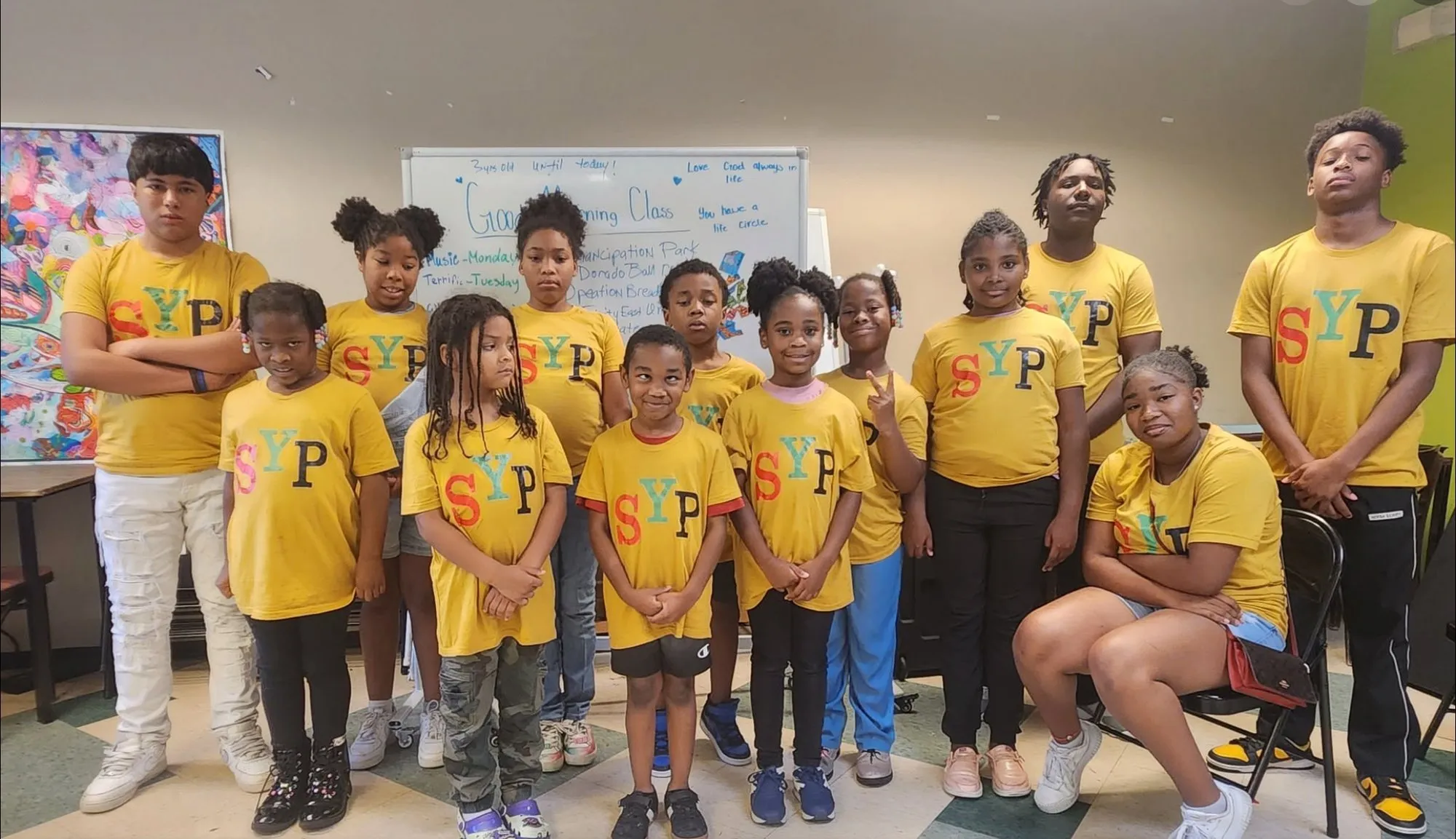 SYP kids and mentors in their gold shirts, gathered in the classroom