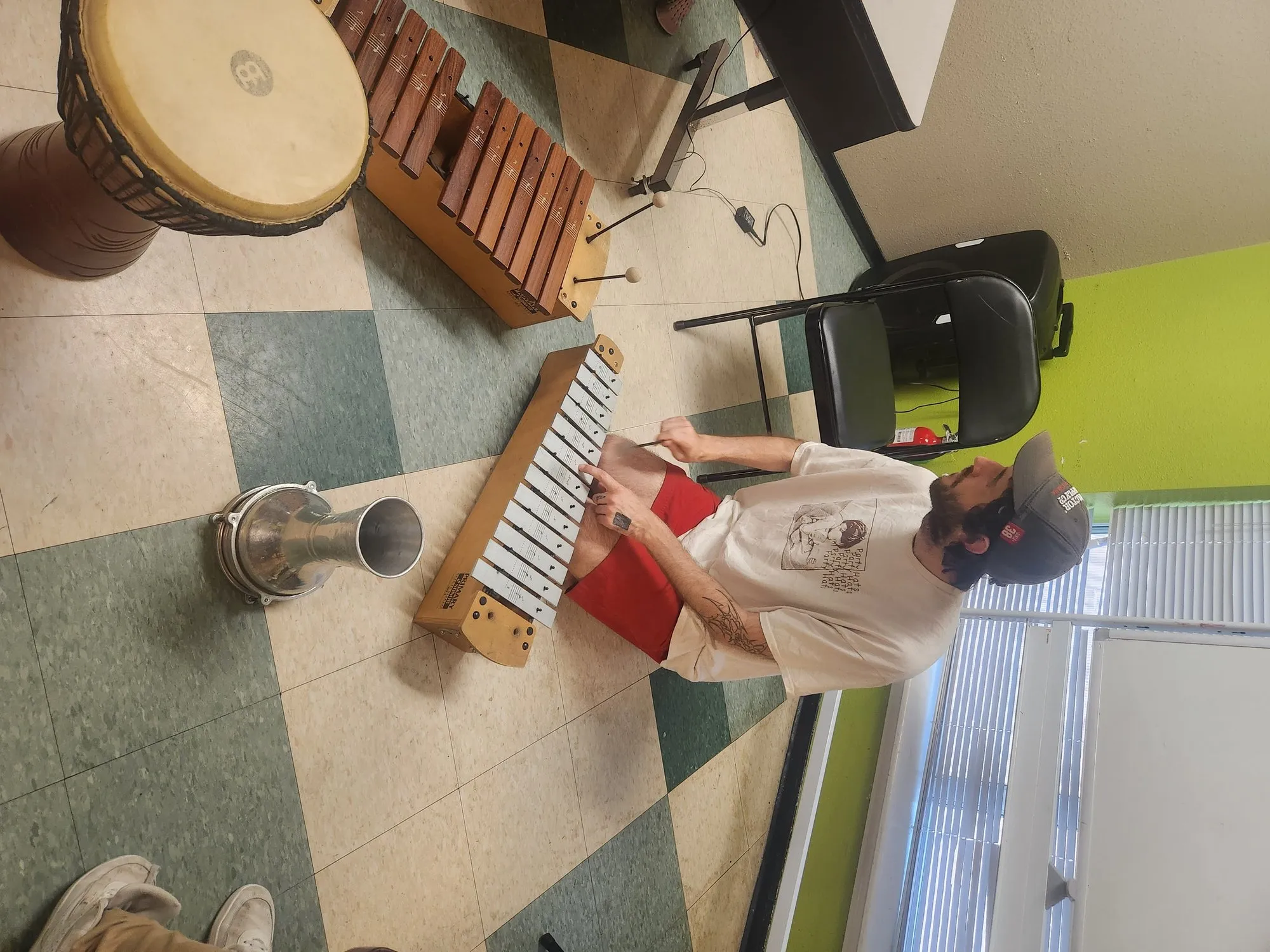 Young man learning keyboard with drums in the background