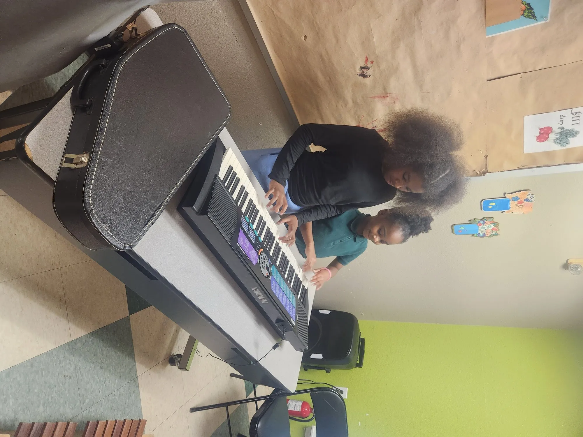 Two girls playing an electronic keyboard together